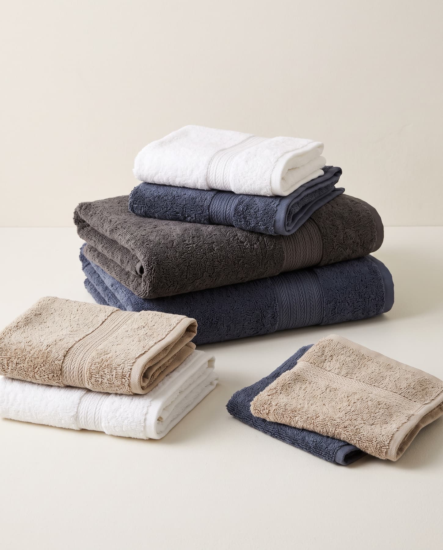 A coordinated set of bath, hand and face towels in white, navy, charcoal and taupe